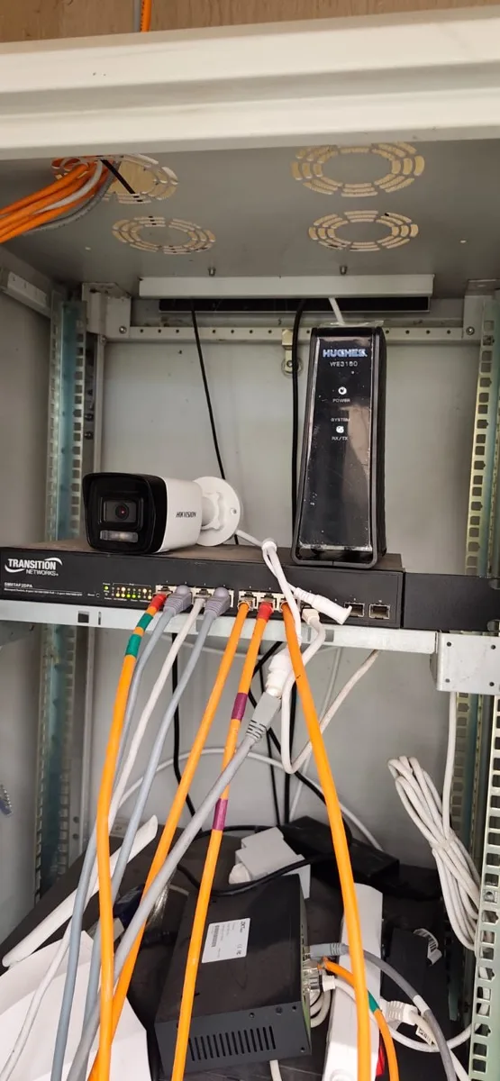Baie réseau regroupant modem satellite Hughes, switch PoE managé et caméra IP Hikvision pour un site logistique près de Rabat